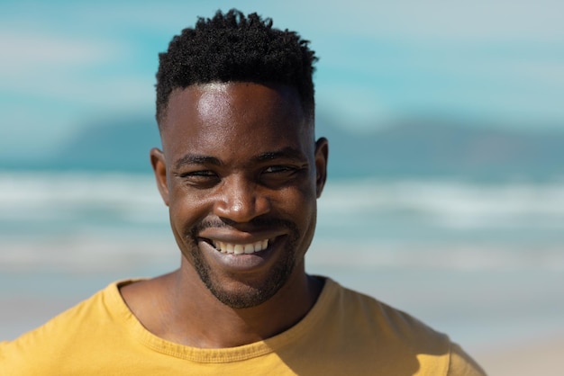 Крупным планом портрет улыбающегося африканского молодого человека на фоне моря и неба в солнечный день