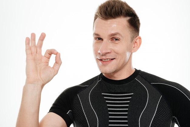 Close up portrait of a smiling athlete man showing ok