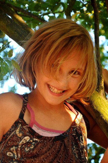 Close-up portrait of smiling girl by trees