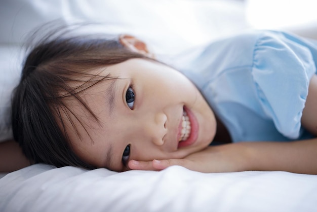 家でベッドに横たわっている笑顔の女の子のクローズアップ肖像画