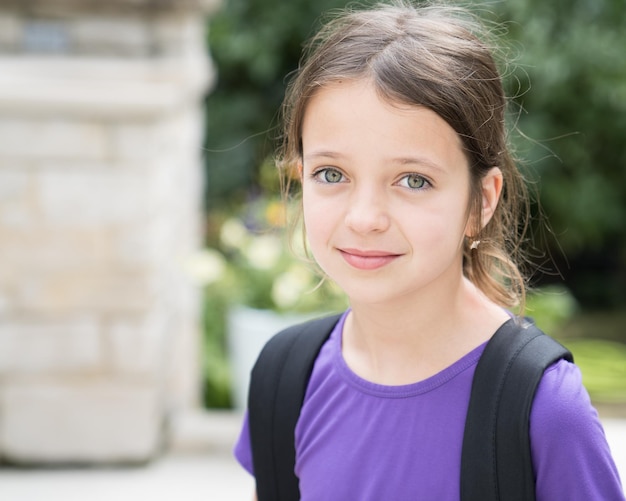 Photo close-up portrait of smiling girl with backpack standing outdoors