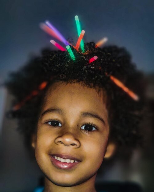 Photo close-up portrait of smiling girl with glowing sticks in hair