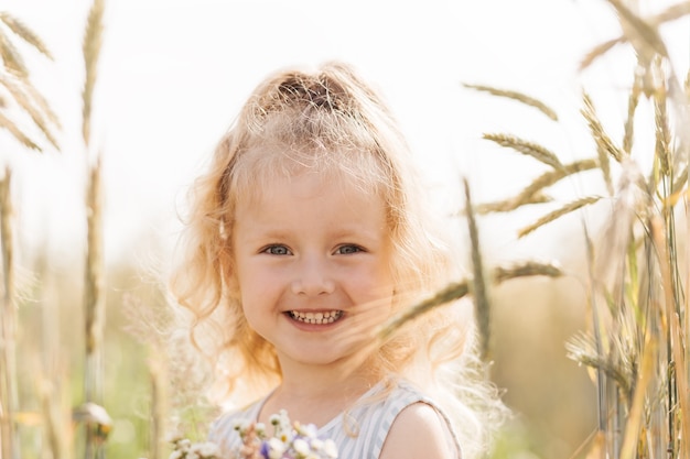 Close-up portrait of a smiling little girl blonde in nature in the summer