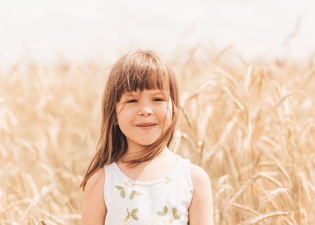 Close-up portrait of a smiling little girl blonde in nature in the summer