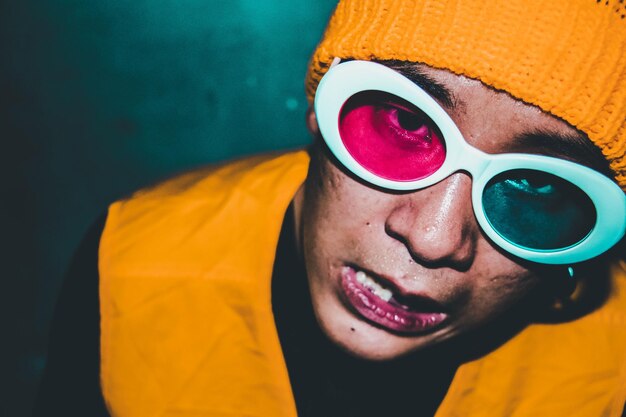 Photo close-up portrait of smiling man wearing colorful sunglasses at home