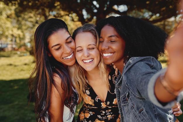 close up portrait of smiling multiracial millennial women laugh stand posing for group picture together group of friends taking a selfie outdoors in the park on a sunny day