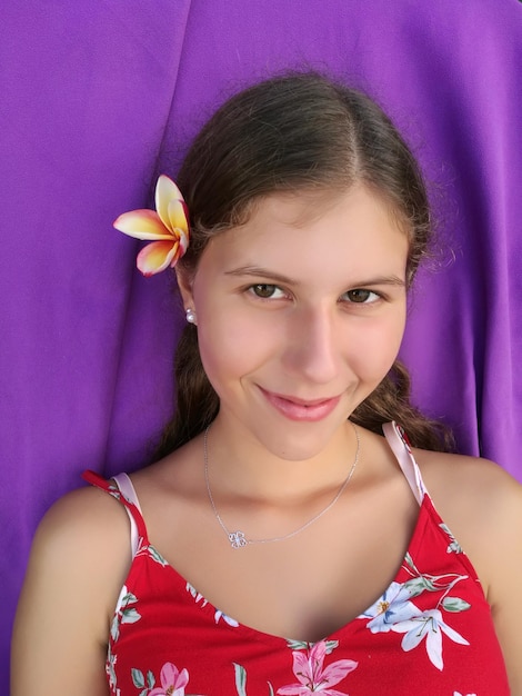 Close-up portrait of smiling teenage girl against purple textile