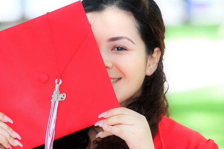 Photo close-up portrait of smiling woman holding red mortarboard