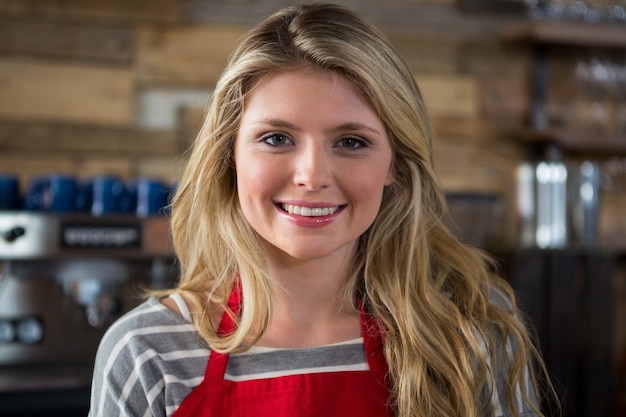 Close-up portrait of smiling young female barista in coffee shop