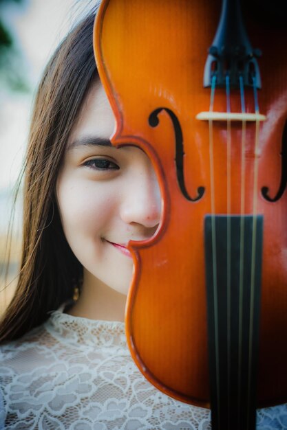 Ritratto ravvicinato di una giovane donna sorridente che tiene il violino contro il viso