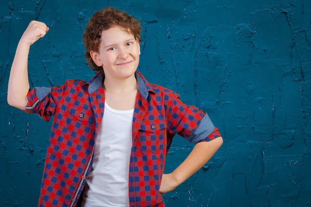 Close up portrait of strong smiling boy showing muscles