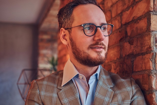 Close-up portrait of a stylish man in a flannel suit and glasses