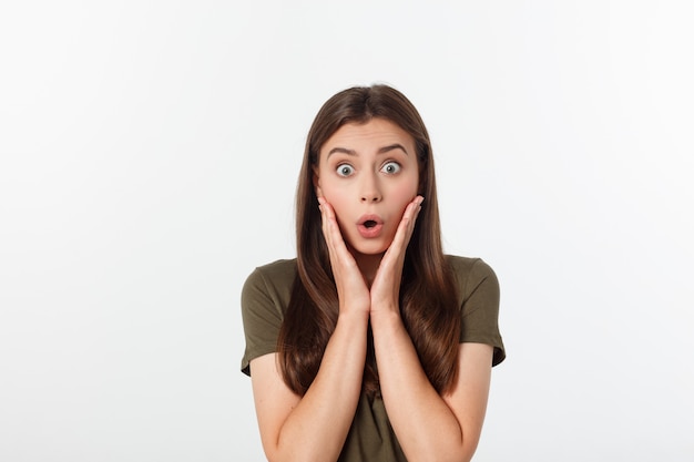 Close-up portrait of surprised beautiful woman holding her head in amazement and open-mouthed. Over white wall