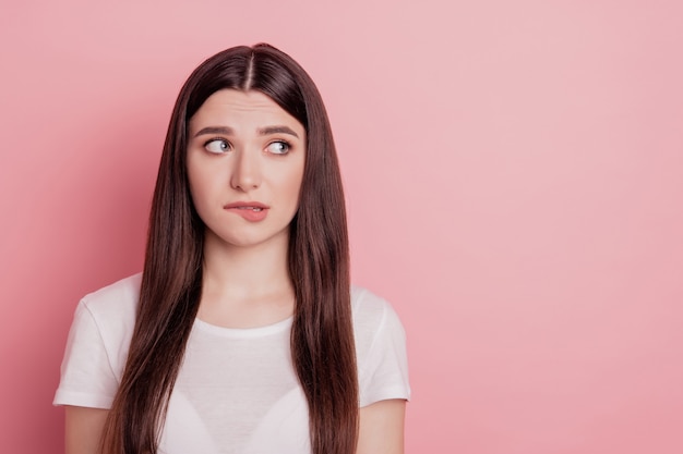 Close up portrait of sweet charming girl nervous look empty space bite lips teeth isolated pink color background