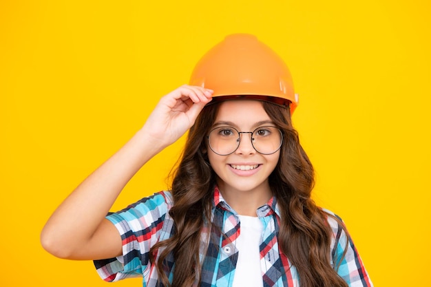 Close up portrait of teenager child builder in helmet Teenage girl on repairing work isolated on yellow background