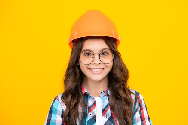 Close up portrait of teenager child builder in helmet Teenage girl on repairing work isolated on yellow background