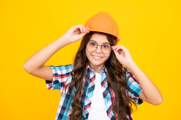 Close up portrait of teenager child builder in helmet Teenage girl on repairing work isolated on yellow background