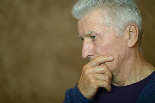 Close up portrait of thoughtful senior man at home