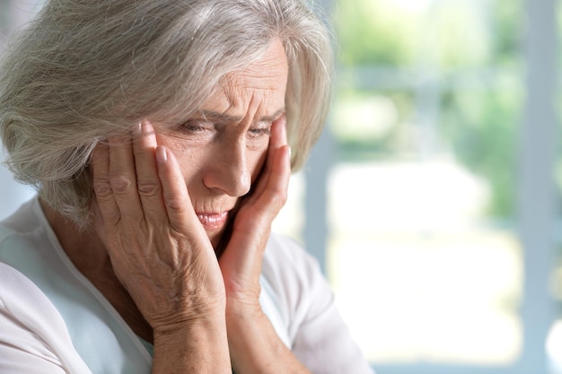 Close up portrait of tired senior woman at home