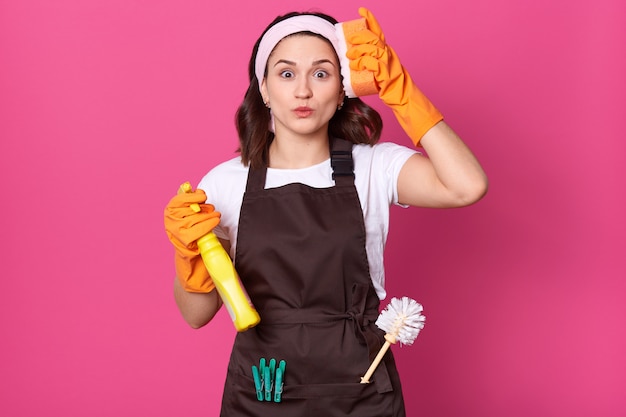 Close up portrait of tired young woman with orange sponge and detergent in hands