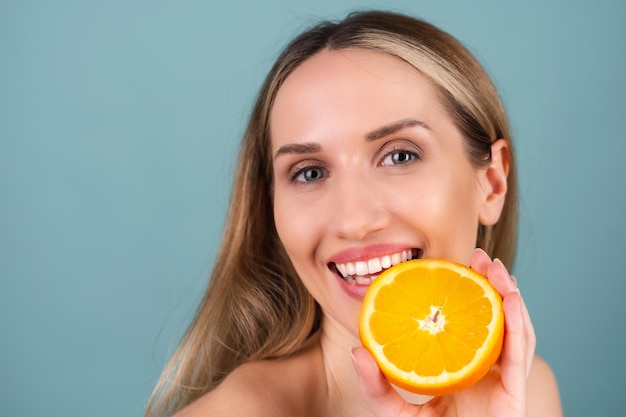 Close-up portrait of topless woman with perfect skin and natural make-up, full nude lips, holding fresh citrus vitamin C orange