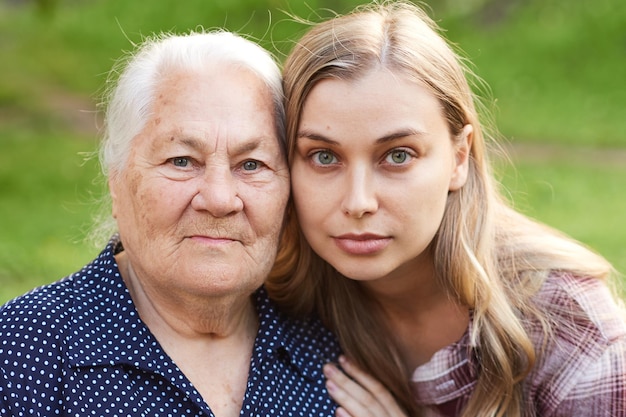 Close up portrait of two generation women grandmother and granddaughter outdoors