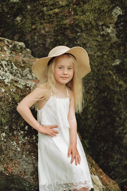 Close up portrait Ukrainian 7 year old girl seat on stone in forest