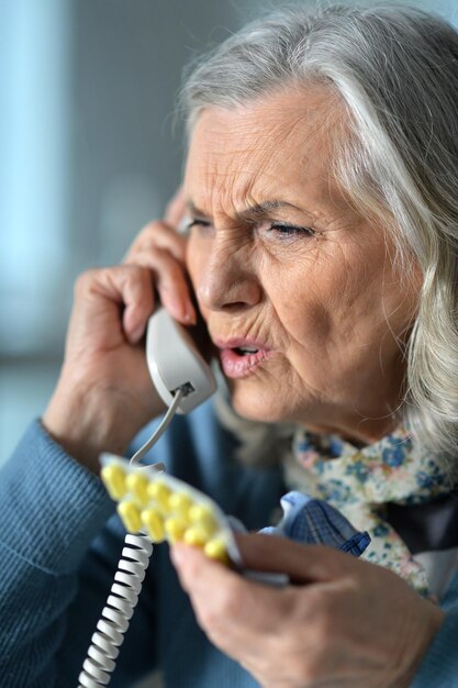 Close up portrait of upset senior woman calling doctor