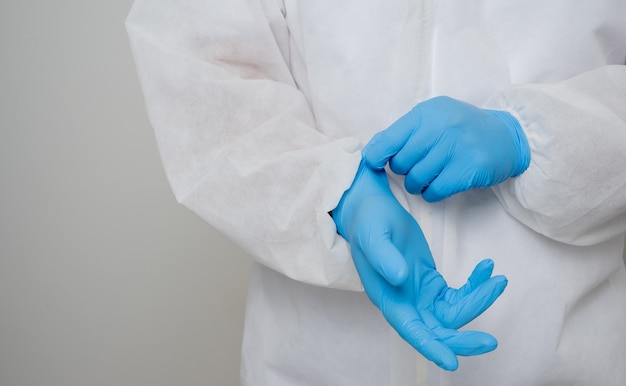 Close up A portrait of virologist put on PPE suit checking blue glove on his hand