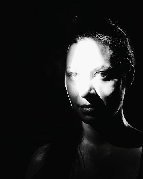 Close-up portrait of woman against black background