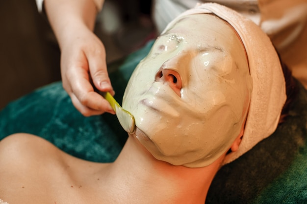 close up portrait of a woman doing skin care procedure while having a alginate mask on her face in a wellness center.