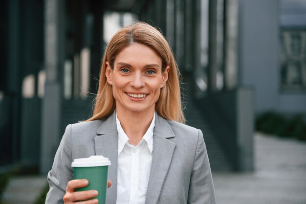 Foto ritratto da vicino donna in abiti formali è all'aperto vicino all'edificio commerciale