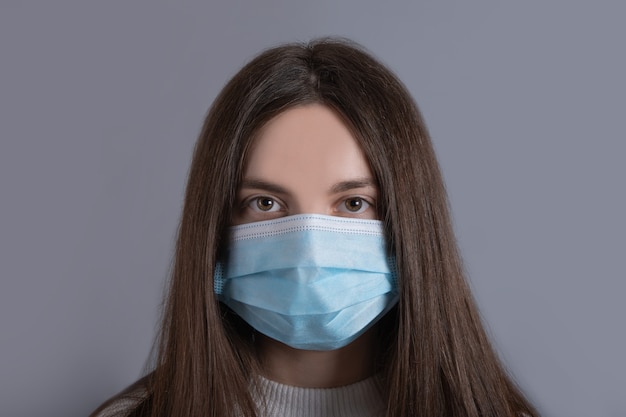 Close-up portrait of woman girl teenager her she nice attractive lovable cute adorable winsome girl with long dark hair wear white sweater protection flu cold facial medical mask