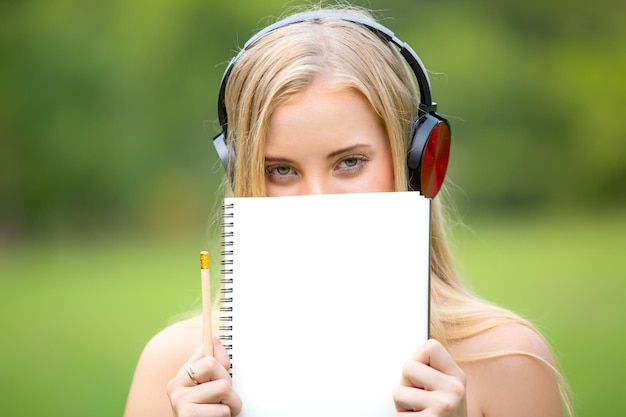 Photo close-up portrait of woman holding book and pencil while wearing headphones