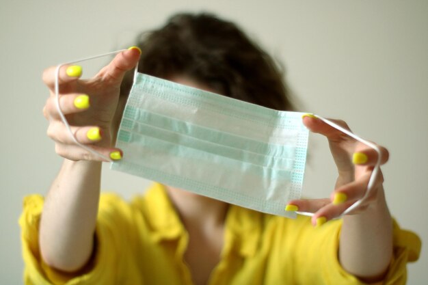 Close-up portrait of woman holding medical mask putting on mask