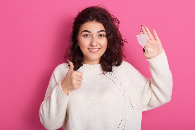 Close up portrait of woman holding menstrual cup isolated over purple studio