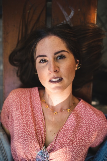 Close up portrait of woman lying in a wooden bench with accessories , golden moon necklace, earrings and perfect white teeth. Beauty and fashion. Cosmetics and skin care.