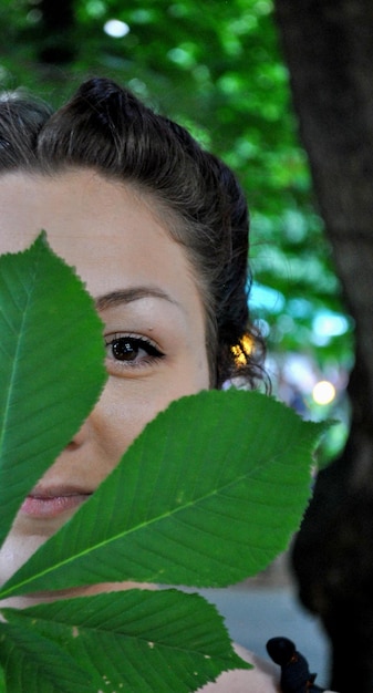Close-up portrait of woman standing behind leaves