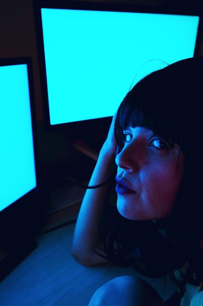 Close-up portrait of woman using computers in darkroom