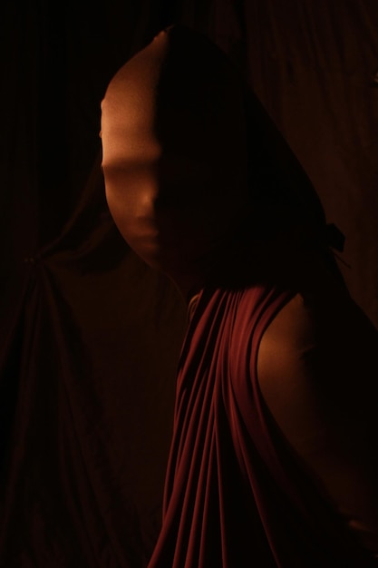 Close-up portrait of woman wearing mask while standing against black background