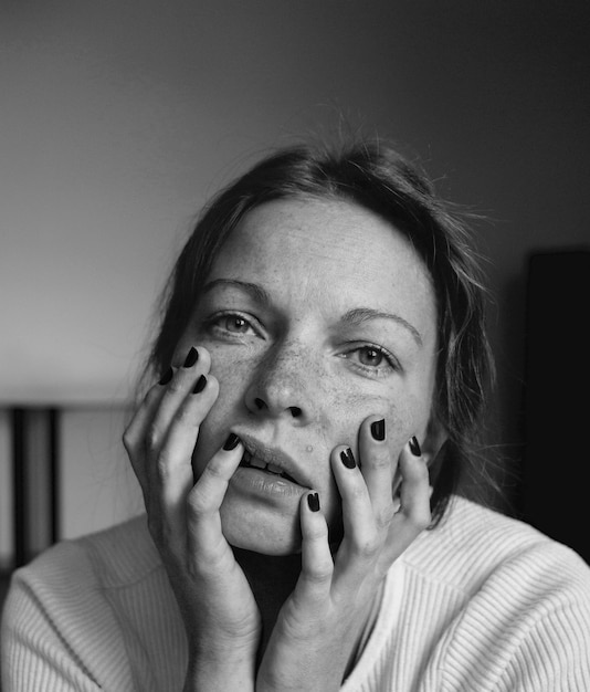 Foto ritratto in primo piano di una donna con le mani sul mento a casa