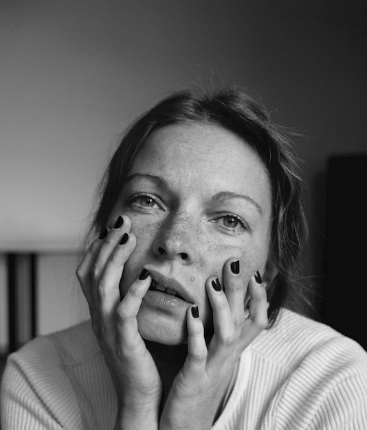 Photo close-up portrait of woman with hands on chin at home