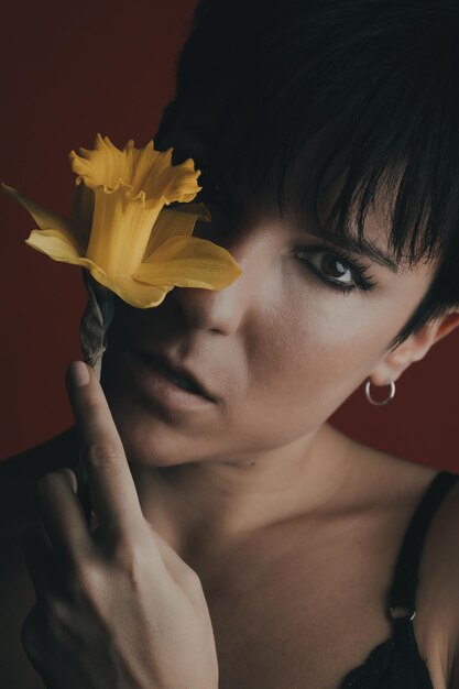 Photo close-up portrait of woman with red flower against black background