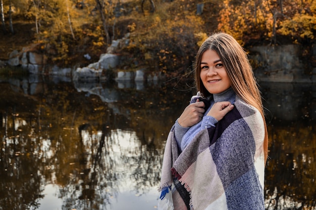 Close-up portrait of a woman with scarf on the lake. Outside. Happy smiling girl. Nature lover