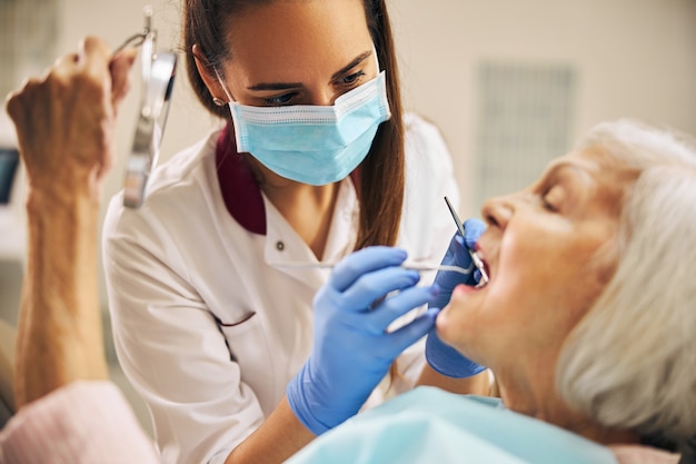 Close up portrait of woman young dentist with elderly beautiful patient during oral checkup in dentistry