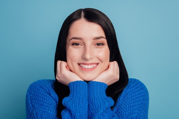 쾌활한 젊은 여성의 클로즈업 초상화 행복한 긍정적인 미소 손은 파란색 배경 위에 격리된 턱을 만집니다.