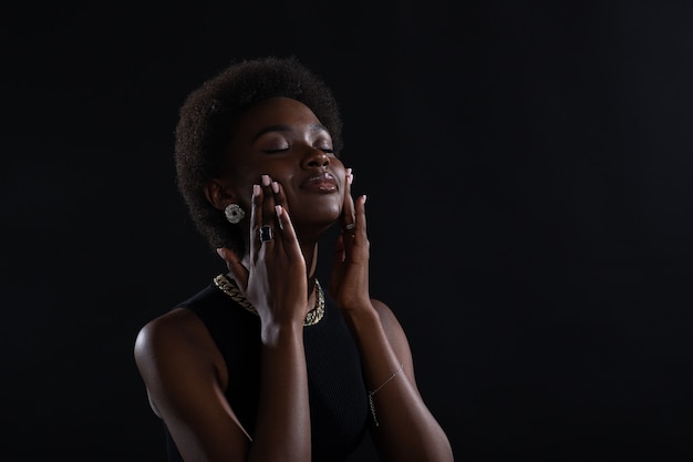 Close up portrait of young african american black woman doing facebuilding yoga face gymnastics yoga self massage cheek.