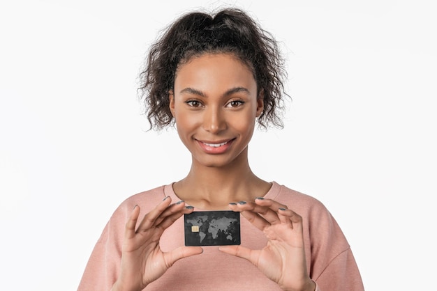 신용카드를 들고 색 배경 위에 고립되어 포즈를 취하는 젊은 아프리카의 행복한 여성의 클로즈업 초상화