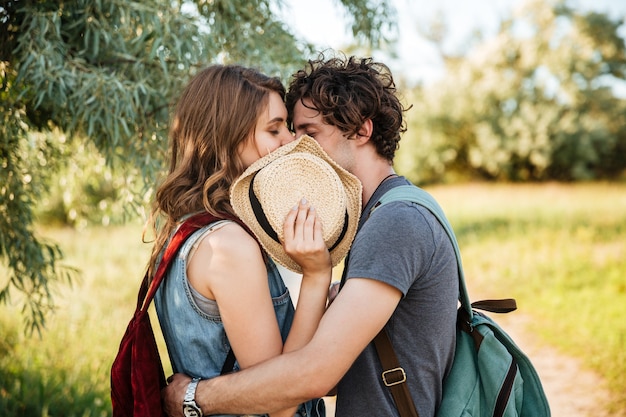 Foto close up ritratto di una giovane coppia attraente in amore che abbraccia con gli occhi chiusi e si bacia su sfondo foresta