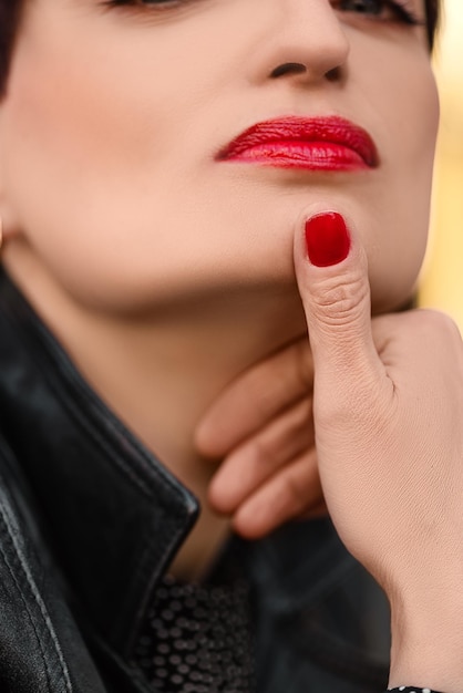 Close up portrait of young attractive woman with red lipstick and red nail polish manicure